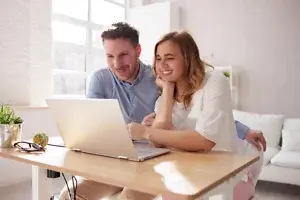 Mann und Frau sitzen am Schreibtisch und schauen gemeinsam auf ein Notebook.