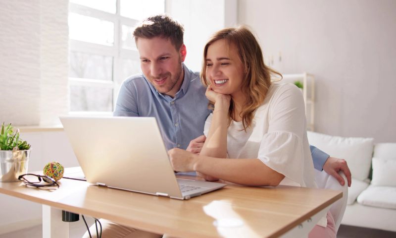 Mann und Frau sitzen am Schreibtisch und schauen gemeinsam auf ein Notebook.